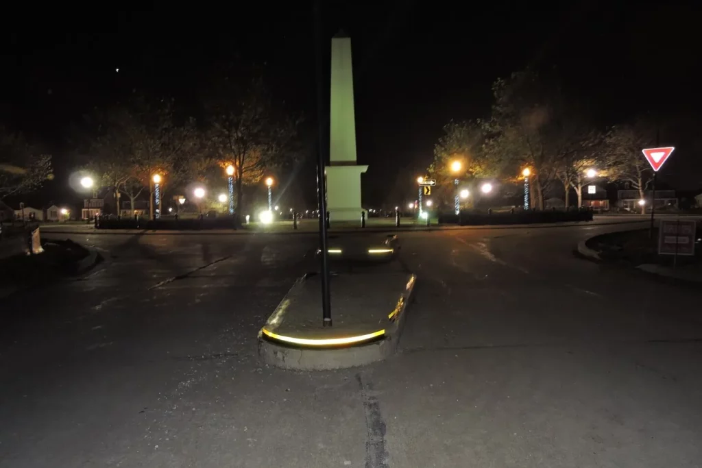 Traffic island at night with reflective markers & streetlights enhancing visibility at a roundabout